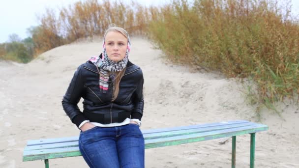Молодая меланхоличка сидит на скамейке у моря . — стоковое видео