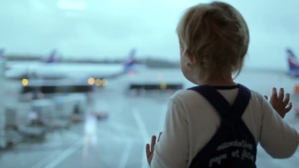 小さな男の子は空港で飛行機を見てください。. — ストック動画