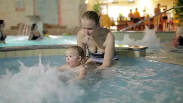 Jeune mère joue avec son fils dans la piscine du spa-salon . — Video