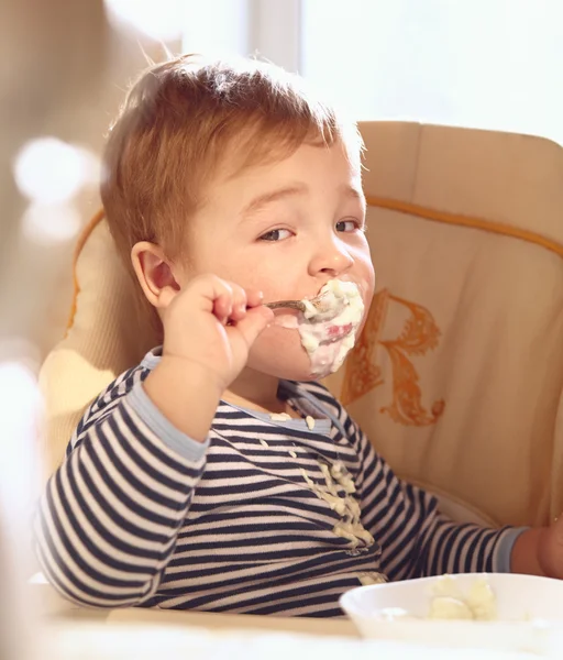 Two year old boy eats porridge in the morning. — Stock Photo, Image