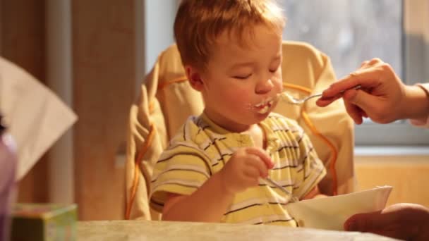 Little boy eats porridge — Stock Video