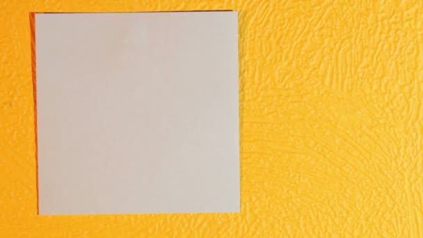 Palos de mano en blanco nota palo rosa en la pared amarilla — Vídeo de stock