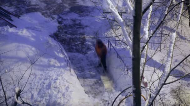 Straat reiniger in oranje uniform verwijderen van de sneeuw — Stockvideo