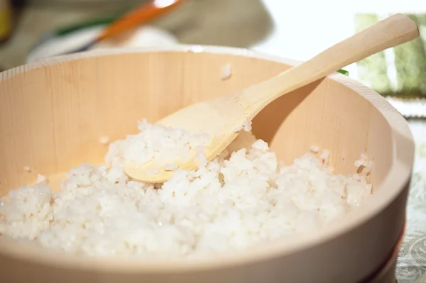 A cozinhar sushi. Misturando arroz em uma placa de madeira . — Fotografia de Stock