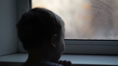 küçük çocuk pencereden görünüyor