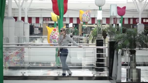 太阳镜的年轻女人说话在购物中心在移动电话上. — 图库视频影像