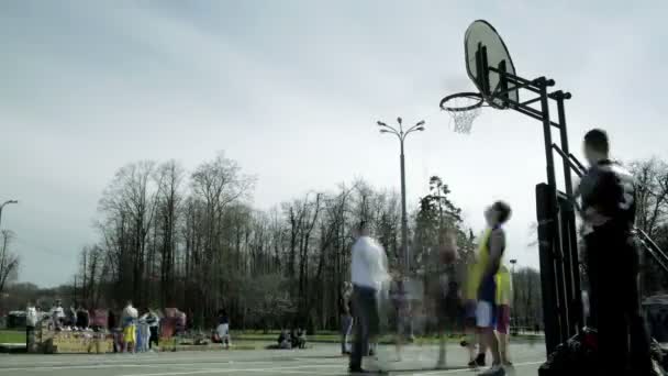 Tieners spelen basketbal in een stadspark. time-lapse — Stockvideo