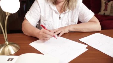 İngilizce öğretmeni masada otururken bir şey yazıyor.