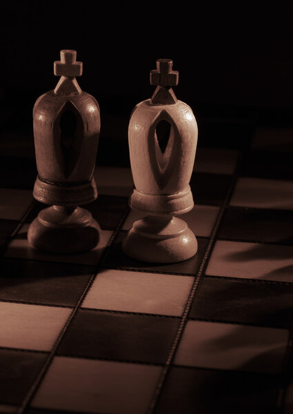 White and black kings on the chessboard opposing each other with copyspace, sepia toned