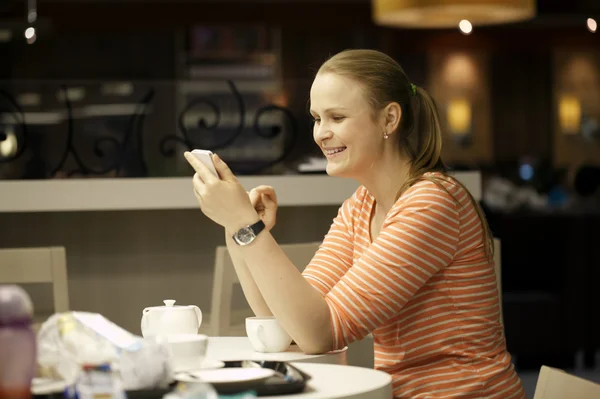 Junge Frau chattet im Café auf Smartphone. — Stockfoto