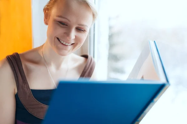 Jonge lachende vrouw lezen van een boek — Stockfoto