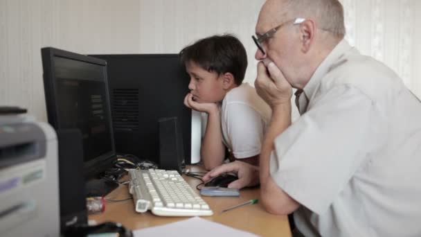 Man aan het werk op de computer, en de jongen vraagt hem een vraag — Stockvideo