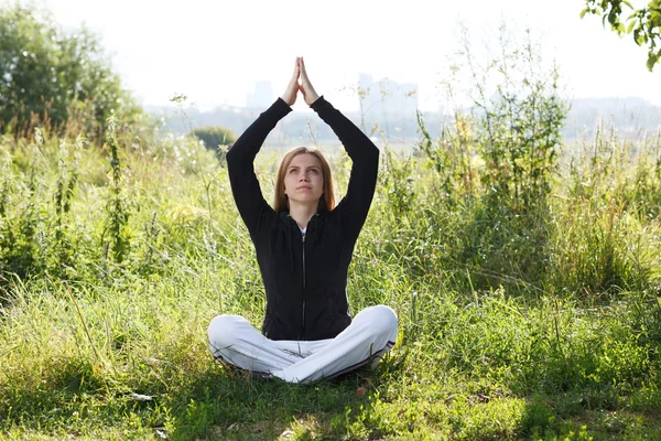 Mladá žena cvičí jógu v městském parku — Stock fotografie
