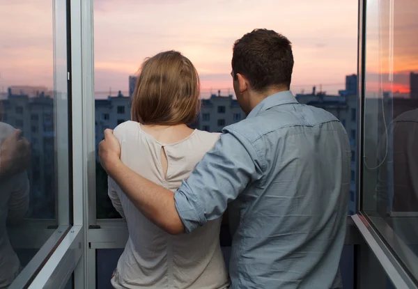 Jeune couple sur le balcon regardant coucher de soleil — Photo