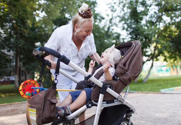 Granny playing with her grandson in pram — Stock Photo, Image
