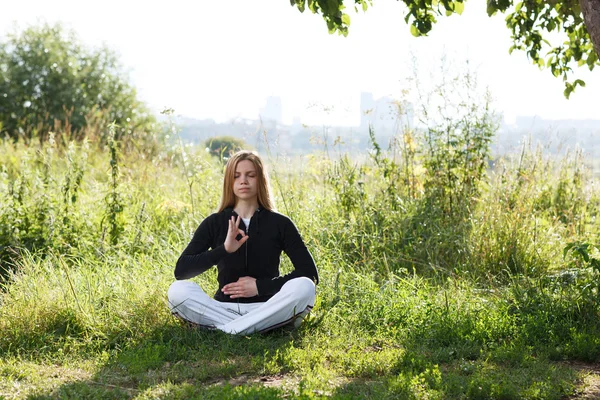 Mladá žena cvičí jógu v městském parku — Stock fotografie