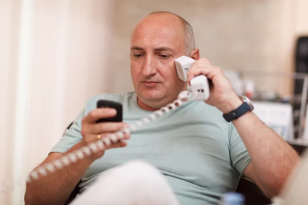 Бизнесмен в офисе говорит по двум телефонам — стоковое фото