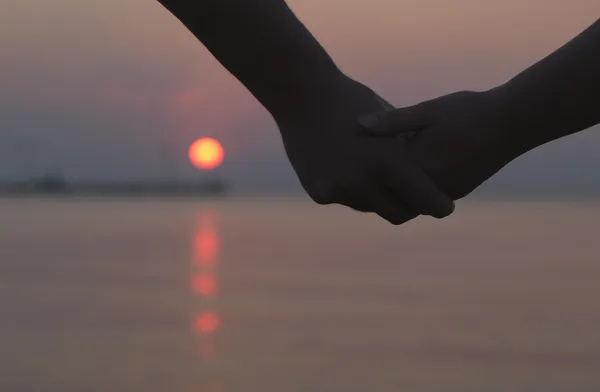 Couple holding hands at sunset — Stock Photo, Image