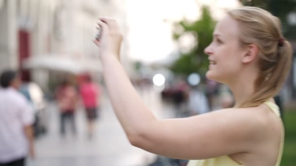 Bella giovane donna bionda che scatta una foto mentre visita la città — Video Stock