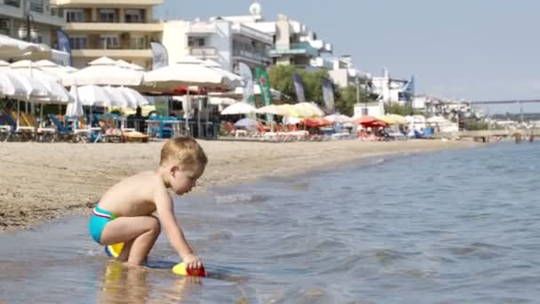 Αξιολάτρευτο μικρό αγόρι που παίζει στη θάλασσα — Αρχείο Βίντεο