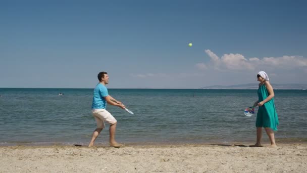 Casal jogando taco e bola jogo de tênis na praia — Vídeo de Stock