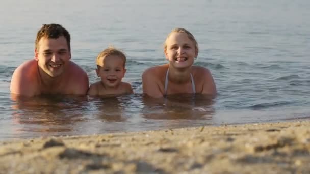 Lachen jongetje geflankeerd door zijn liefhebbende ouders — Stockvideo