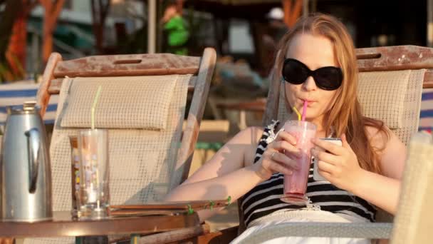 Aantrekkelijke vrouw dragen van een zonnebril ontspannen in een strandstoel in de zon — Stockvideo