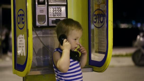 小男孩说话的手机在一个黄色的电话亭 — 图库视频影像