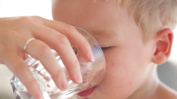 Cute little boy drinking a glass of fresh water being held by his mother — Stock Video