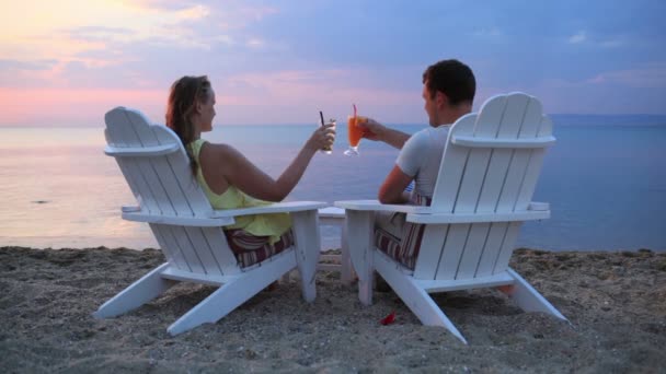 Pareja romántica sentada en tumbonas de madera en la playa — Vídeo de stock