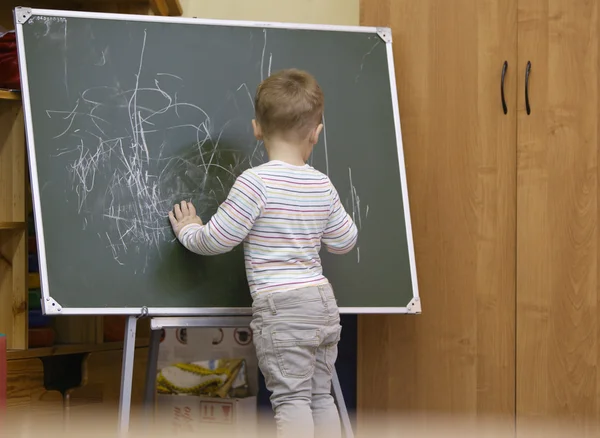 Kleine jongen tekening op een schoolbord op kleuterschool — Stockfoto