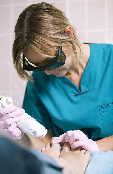 Médico fazendo um tratamento a laser em um pé de mulher — Fotografia de Stock