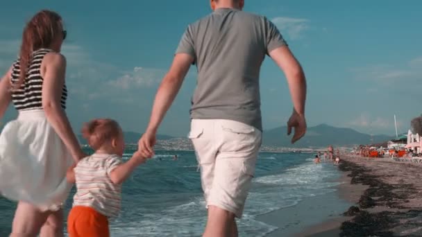 Muž a jeho manželka, oba drží za ruce jejich dítě — Stock video