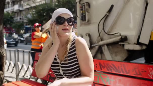 Mladá žena v sluneční brýle a bílým šátkem trvá hovor — Stock video