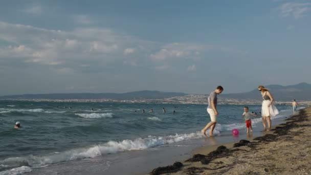 Šťastný mladí rodiče a jejich malý syn hrát fotbal na pláži — Stock video