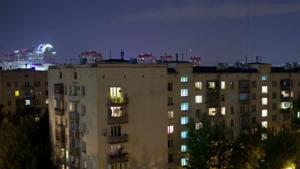 Tijdspanne van multistorey gebouwen met wisselende venster verlichting 's nachts en volgende sluiten-omhoog — Stockvideo