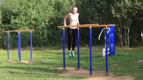 Fille sportive faisant de l'exercice sur des barres parallèles sur un terrain de sport — Video