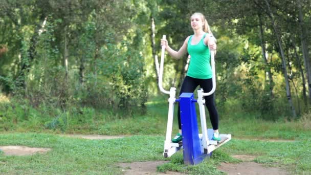 Mujer joven sana en forma haciendo ejercicio en un entrenador en el jardín — Vídeos de Stock