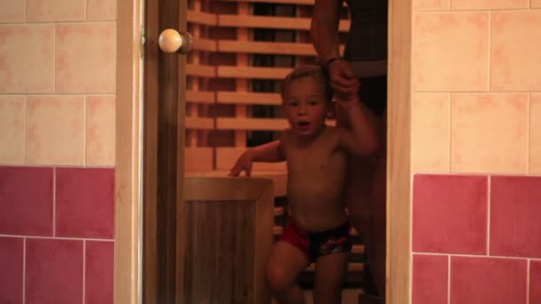 Madre y su hijito saliendo de la sauna y cerrando la puerta de cristal — Vídeo de stock