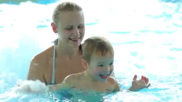 matka a její malý syn hraje v hrubé vodě bazénu. rodinnou zábavu v aquaparku