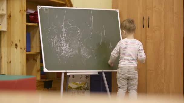 Creatieve kleine jongen tekening op een schoolbord — Stockvideo