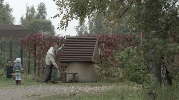 Grandfather and grandson near well. — Stock Video