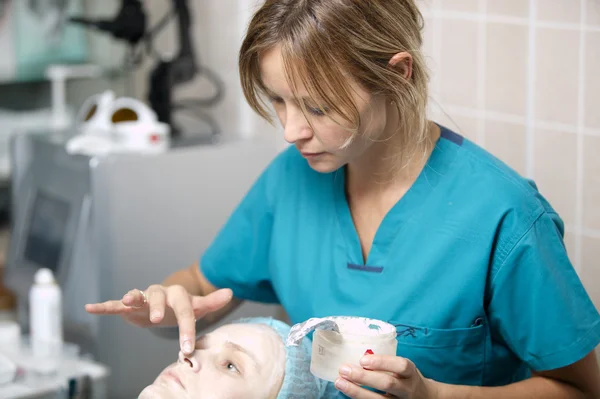 Infirmière dans une clinique cutanée appliquant une crème protectrice — Photo