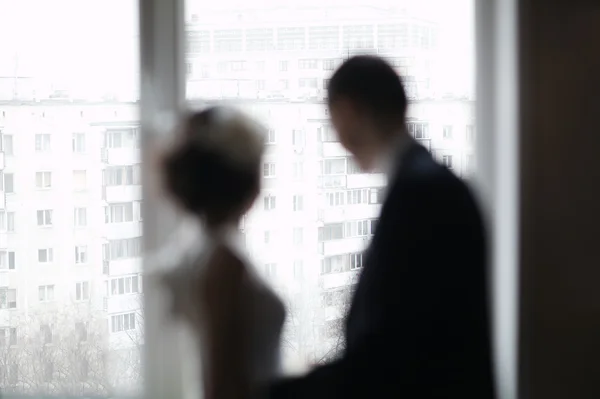 Свадебная пара смотрит в окно — стоковое фото