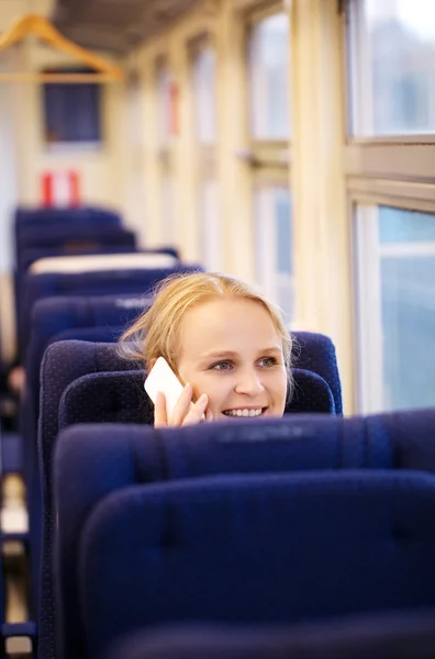 Smiling woman talking on the phone in train. — Stock Photo, Image
