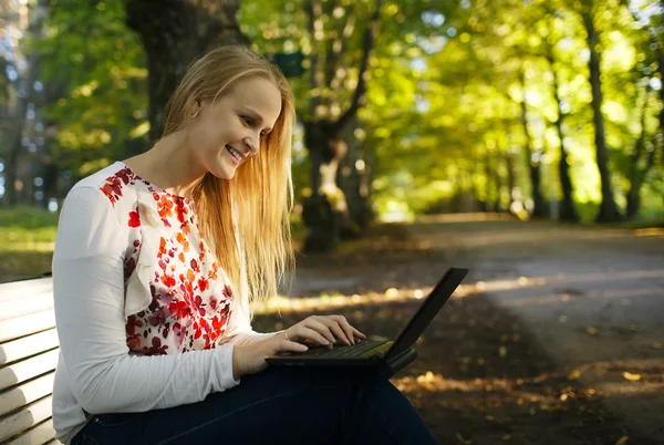 Mladá žena pomocí její laptop v parku — Stock fotografie