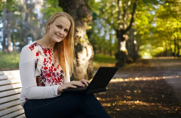 Jeune femme utilisant son ordinateur portable dans le parc — Photo