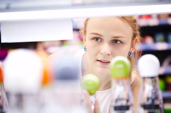 Jonge vrouw analyseren van producten in een winkel — Stockfoto
