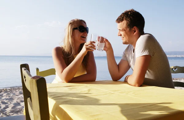 Pareja joven disfrutando de bebidas en la playa — Foto de Stock