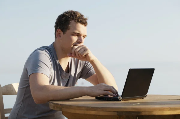 Hombre escribiendo en un pequeño ordenador portátil —  Fotos de Stock
